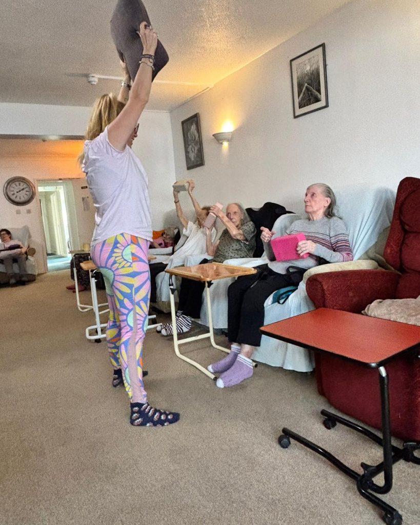 Elderly residents doing seated exercises with an instructor in a care home