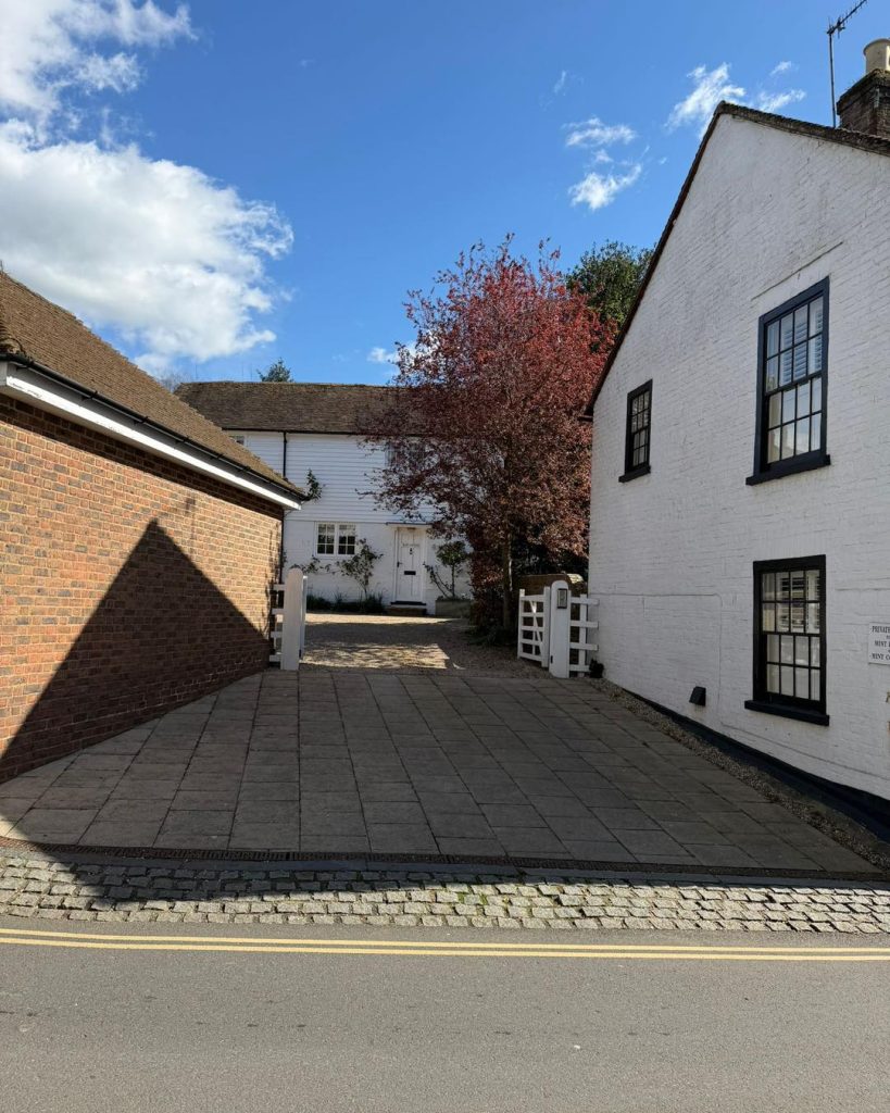 Quiet courtyard with white and brick buildings, a tree with red leaves, and blue sky.
