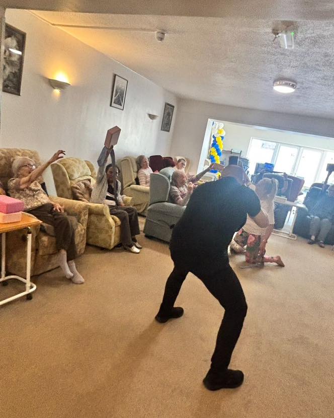 Group activity in a care home with residents participating while a photographer takes pictures.