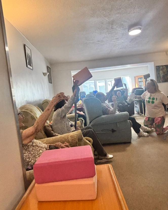 Seniors raising foam blocks in the air during an interactive care home activity.