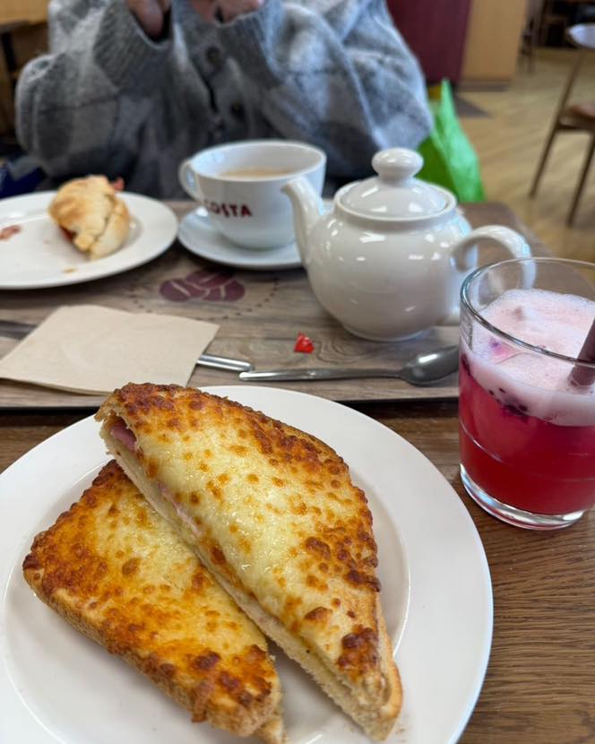 Cheese toast on a plate with tea and a pink drink on a café table
