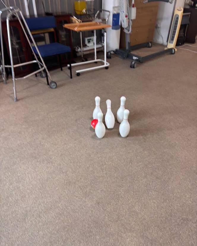 Resident taking part in an indoor bowling game during a fun activity session.