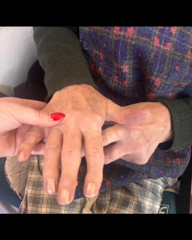 Caregiver holding an older adult’s hand while showing freshly manicured nails.