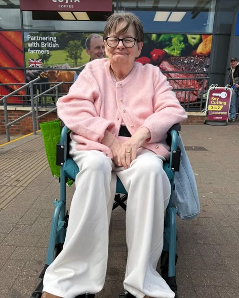 Resident smiling while enjoying an outdoor trip in a wheelchair.
