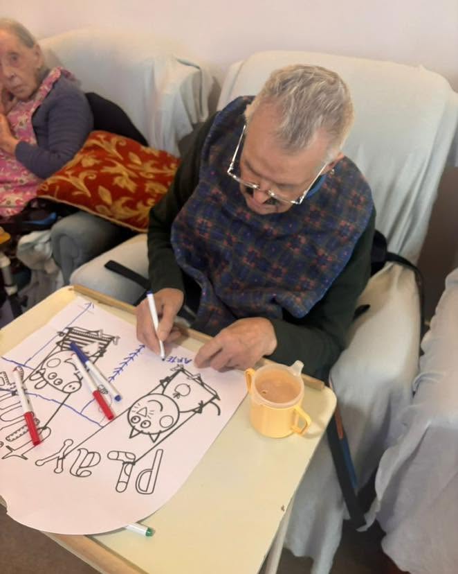 Resident enjoying a creative colouring activity in a comfortable care home setting.
