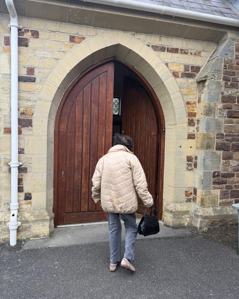 Resident entering the church through the wooden arched doorway.
