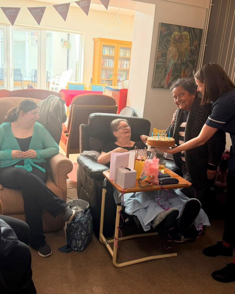 Resident celebrates birthday with staff and visitors gathered around.