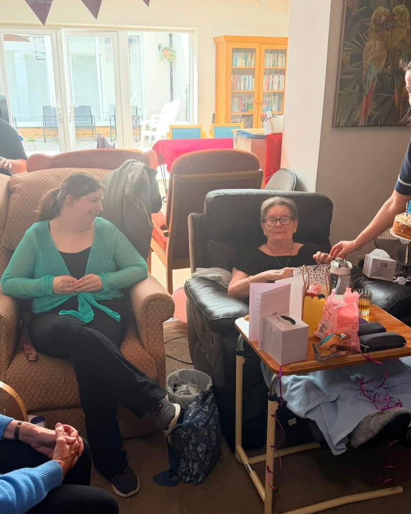 Resident sits with family and gifts during a birthday gathering.