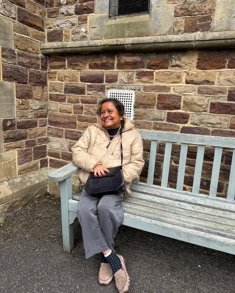 Resident smiling while seated on a bench outside the church.