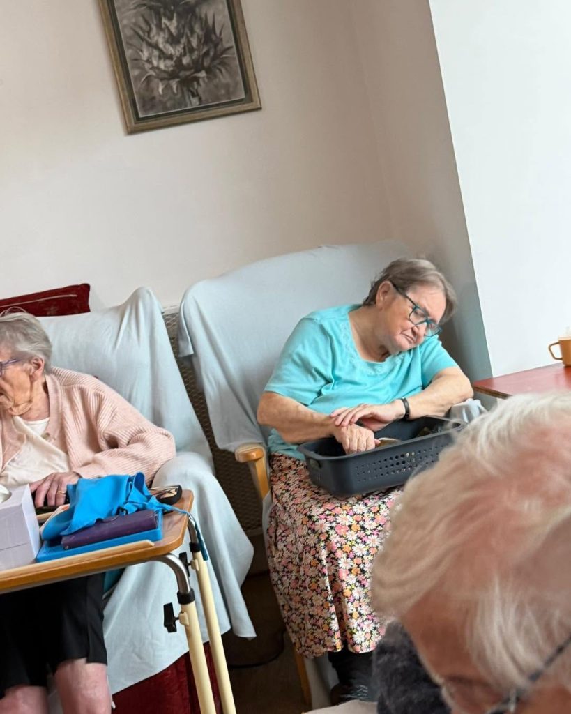 Residents relaxing while interacting with a guinea pig in a calm nursing home lounge.