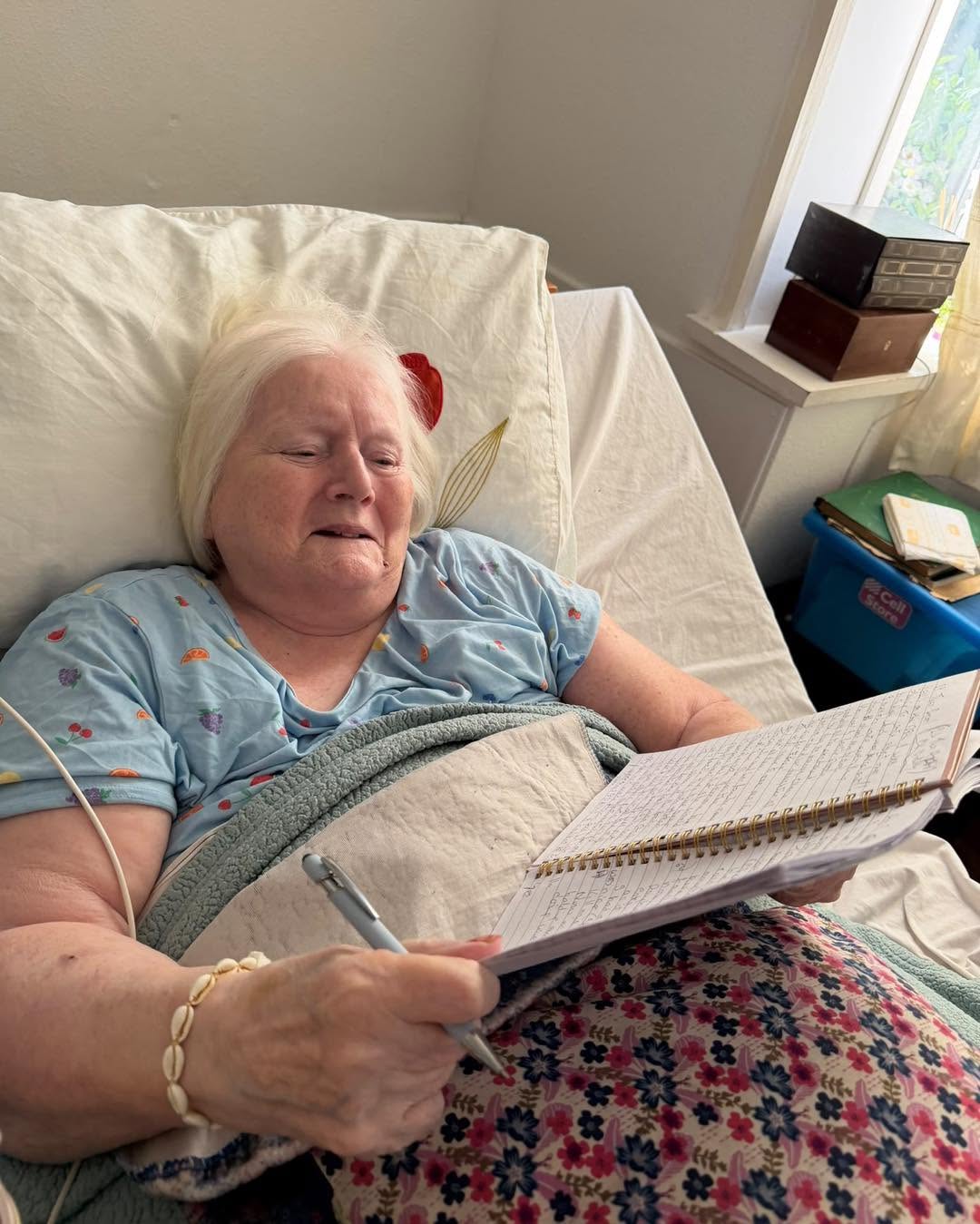 Older woman smiling while writing in a notebook.
