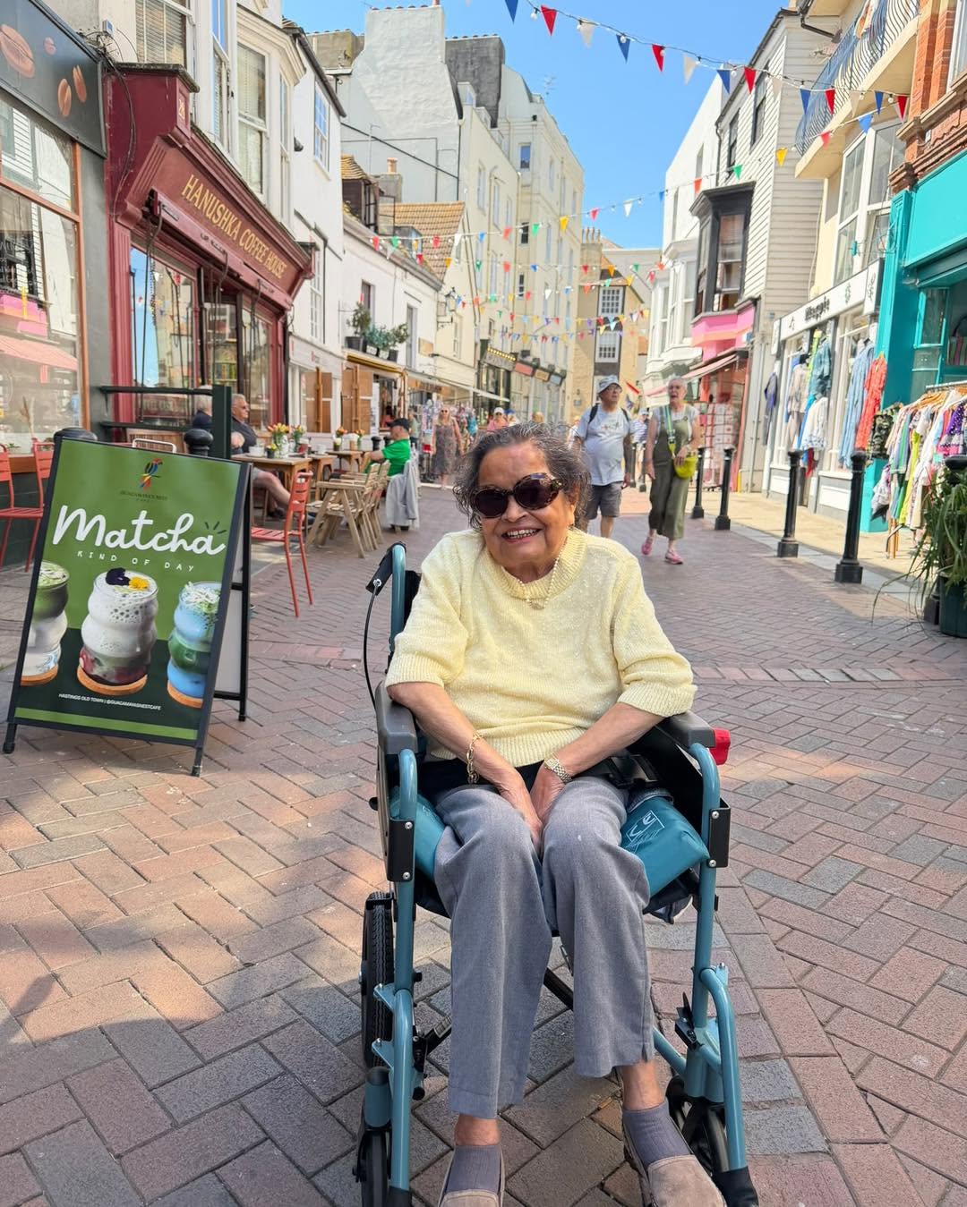 Elderly woman smiling while exploring a shopping street in her wheelchair